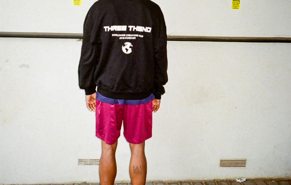 DomiKriss posing for Three Thousand Clothing in black tee and pink shorts