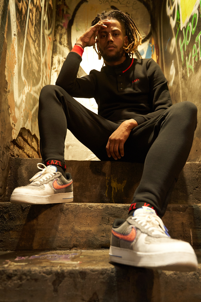 DomiKriss on a brick staircase, concrete street, wearing Nike shoes.